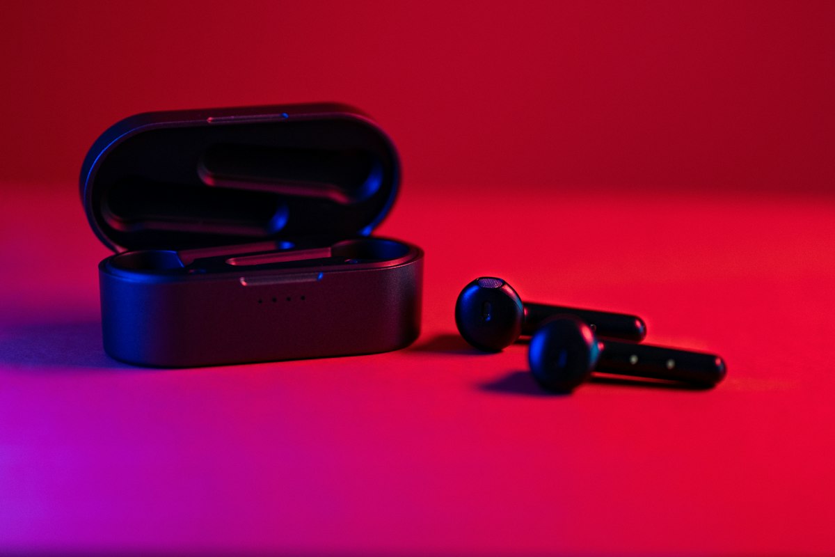 赤い照明の中に置かれたワイヤレスイヤホンと充電ケース